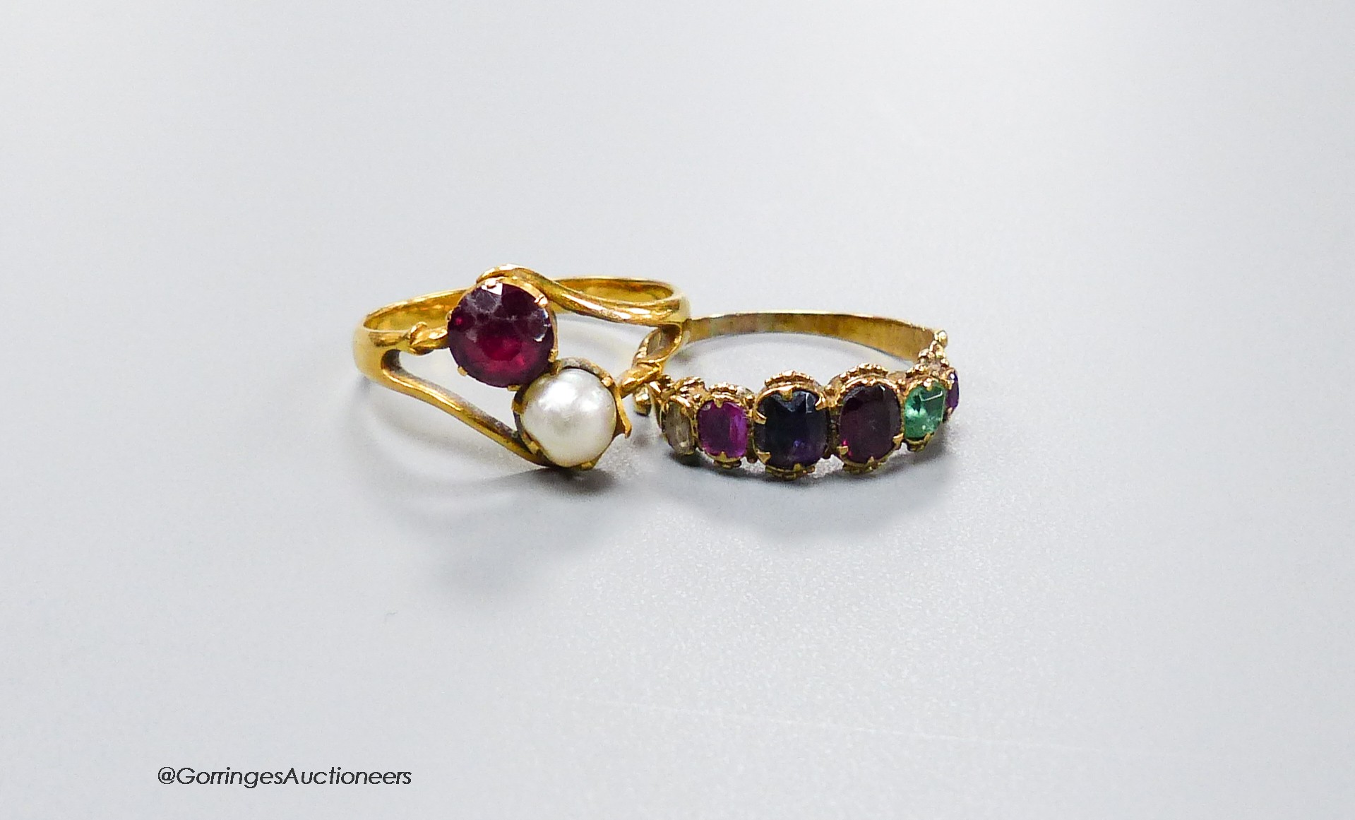 A Victorian yellow metal and graduated multi gem set 'Regard' half hoop ring, size L and a yellow metal ruby and cultured pearl set crossover ring, size O, gross weight 4.7 grams.